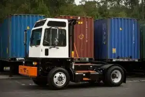 What Makes the TICO Yard Spotter Truck Different? | Renew Truck in Boston, TX. Image of a white TICO terminal tractor with container vans in the background. From TICO media room (https://ticotractors.com/media-room/).