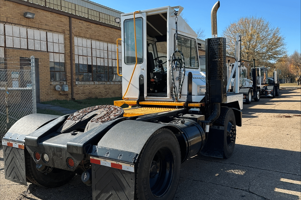 Yard truck repair costs, spotter truck repair in New Boston, TX at Renew Truck. Rear view of a yard truck (terminal tractor) parked outside an industrial building with several other yard trucks lined up in the background.