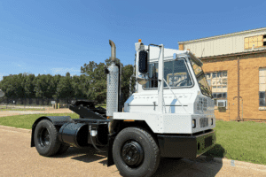 Yard Truck Jockeys in New Boston, TX by Renew Truck. White yard truck parked outside an industrial building on a sunny day, showing its side and front view.